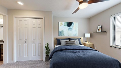 A bedroom with a bed, a ceiling fan, and a painting on the wall.