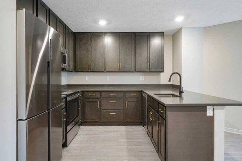 A U-shaped kitchen featuring dark cabinets and stainless steel appliances