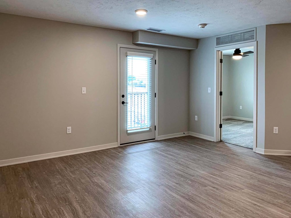 a living room with a door to a balcony and a door to a bedroom