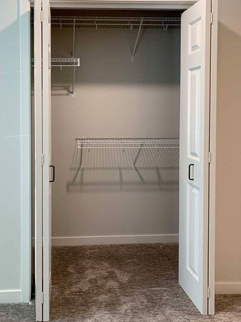 a closet with white doors and built-in shelving and hanging space
