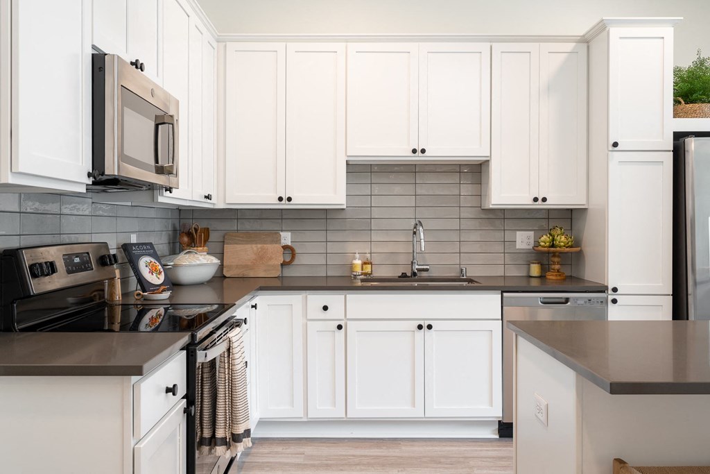 Kitchen with white cabinetry stainless steel appliances and dark countertops