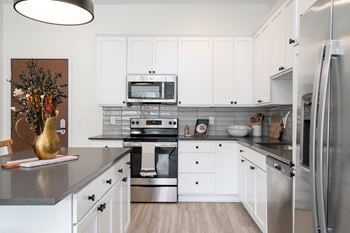 Kitchen with white cabinetry stainless steel appliances and dark countertops