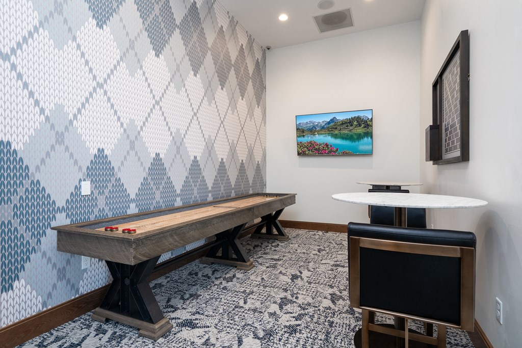 Shuffle board game on the left wall with small table and two chairs on the right