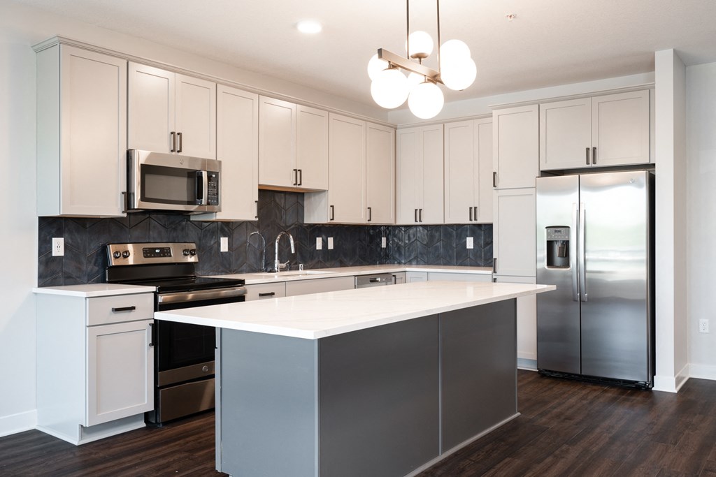 Beautiful white kitchen with matching stainless steel appliances and large kitchen island.