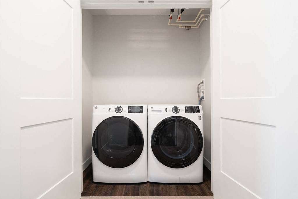 washer and dryer side by side in laundry closet with doors open