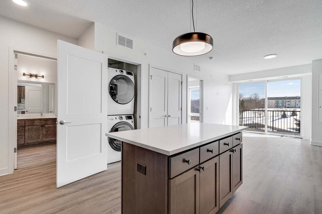 Kitchen island counter space with hidden stacked washer and dryer at The Rowan in Eagan Minnesota