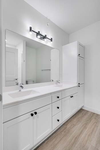 TheRowanLuxuryApartments Bathroom with white double vanity and linen cabinet for storage and large mirror at The Rowan in Eagan Minnesota - Photo Gallery 4