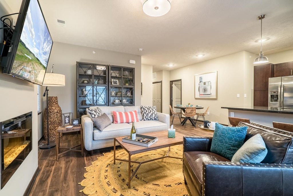 A modern living room with a fireplace and a large TV mounted on the wall.