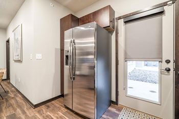 A stainless steel refrigerator is in a kitchen with wood cabinets.