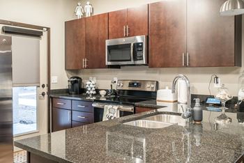 A kitchen with cherry cabinets, granite counter top and stainless steel appliances.