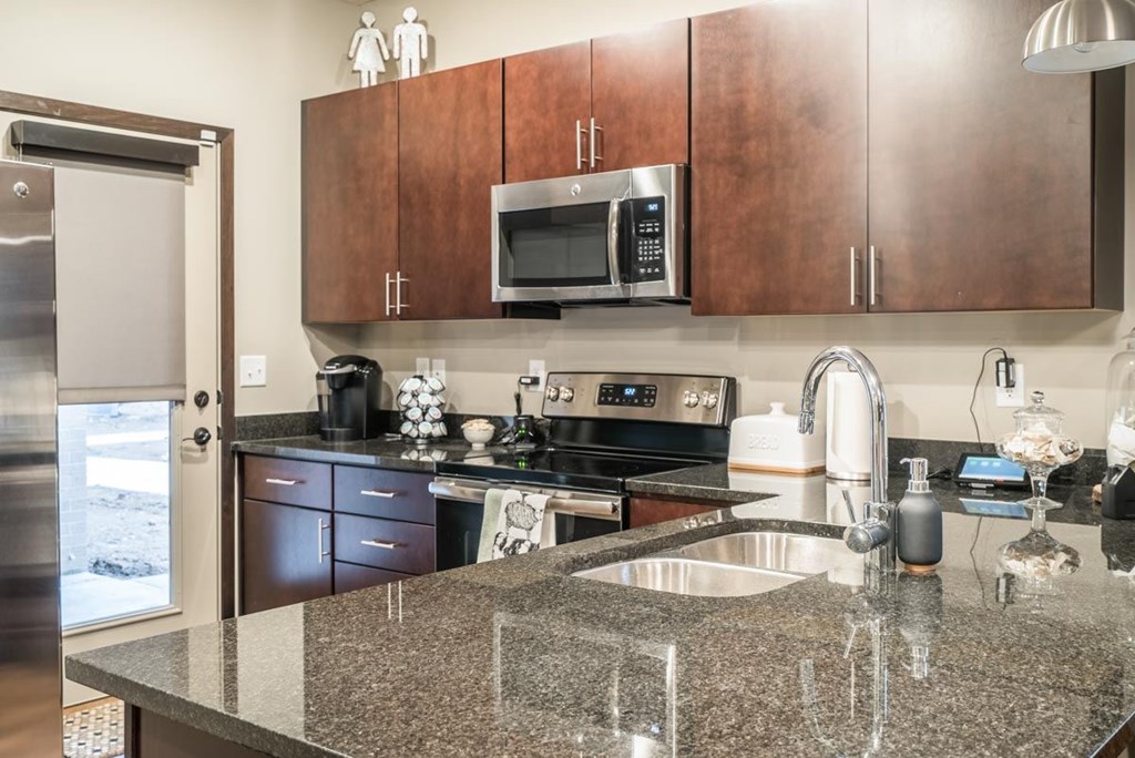 A kitchen with cherry cabinets, granite counter top and stainless steel appliances.