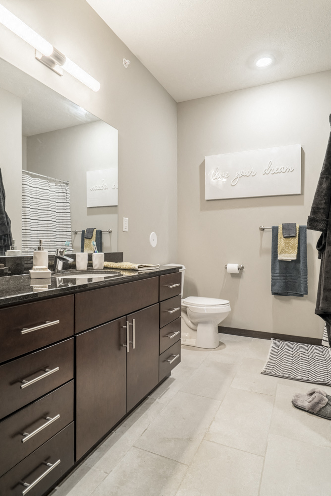 Interiors-Bathroom in traditional design scheme with dark cabinetry, light tile floors and granite countertops