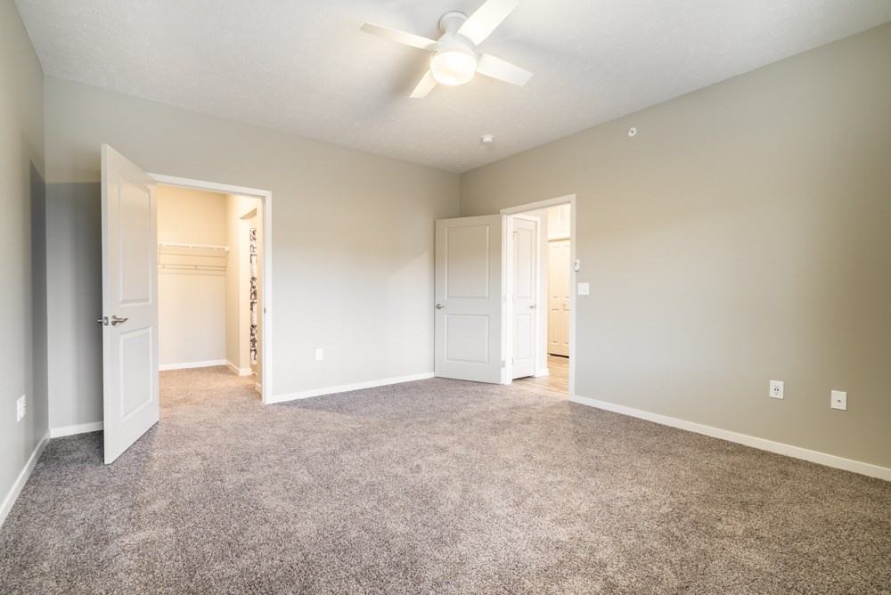 A spacious room with a ceiling fan and carpeted floor.