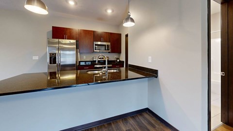 A kitchen with a stainless steel refrigerator and cherry wood cabinets.