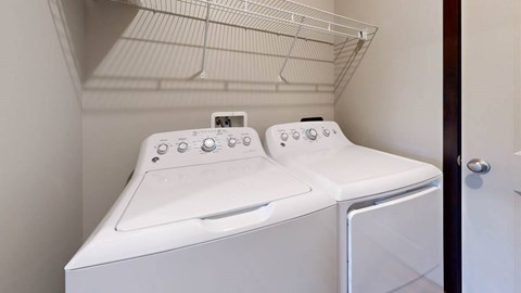A white washer and dryer with a shelf above them in small laundry room