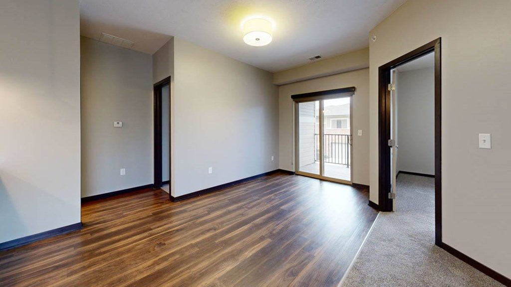 A room with wooden flooring and a sliding glass door.