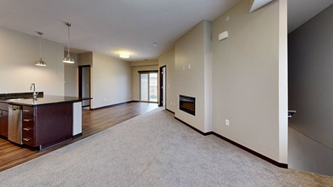 A spacious living room with a kitchen area and a fireplace.