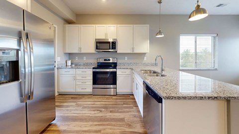 A modern kitchen with stainless steel appliances and wooden flooring.