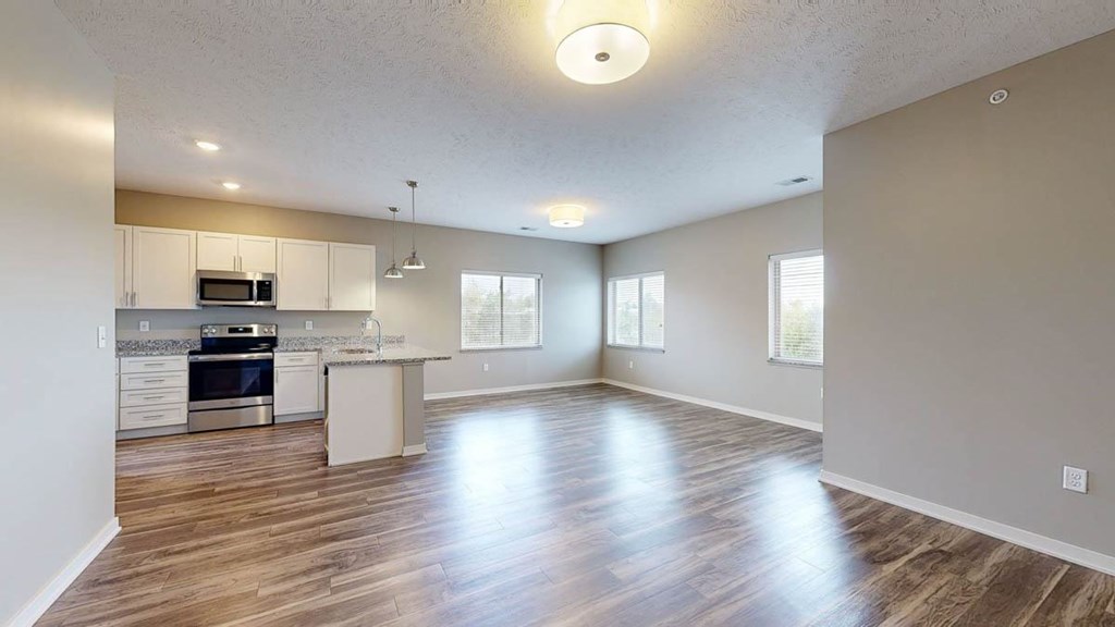 A spacious kitchen and living room with wood floors and white walls.
