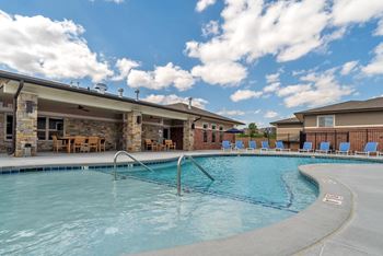 A large outdoor swimming pool with a stone building in the background.