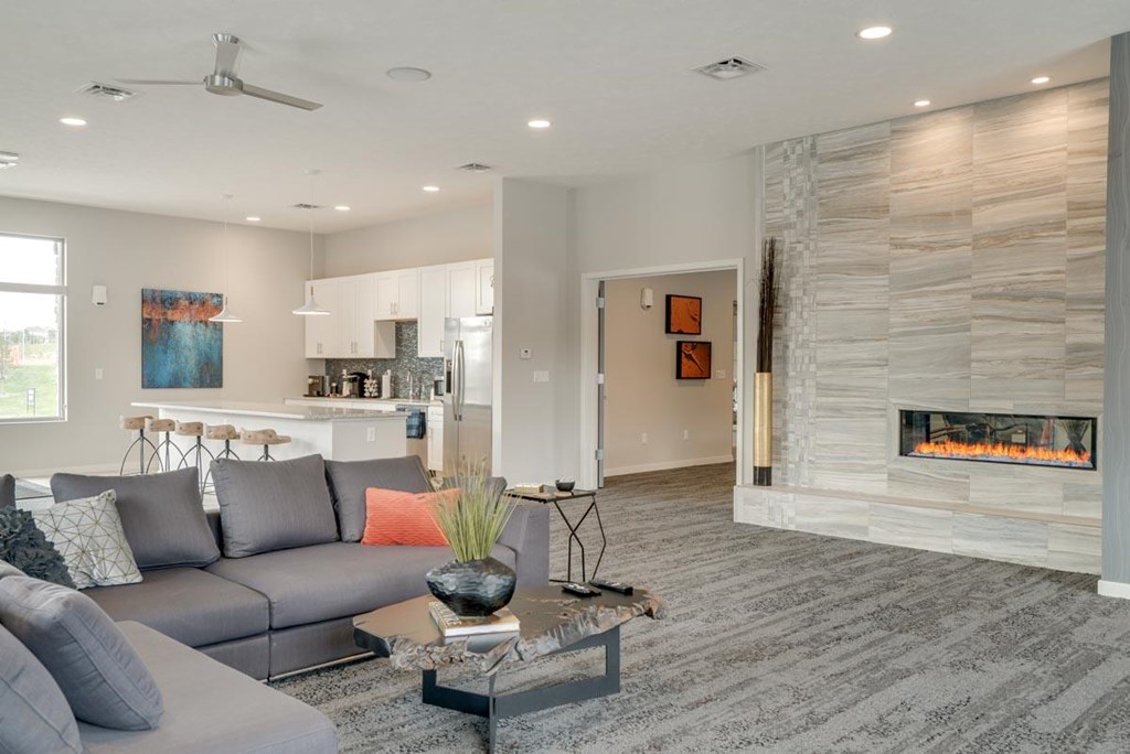 A modern clubhouse great room with a grey sofa and a fireplace.