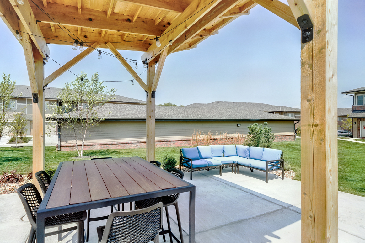 Outdoor patio with table and couch, covered by wooden pergola