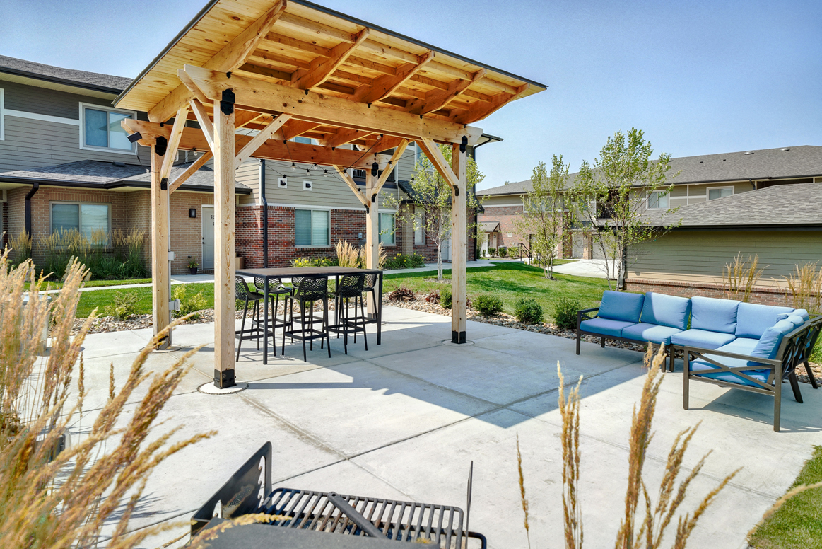 Outdoor patio with table and couch, covered by wooden pergola