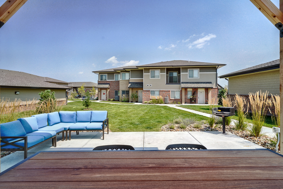 Outdoor patio with table and couch with blue cushions near the clubhouse at Villas at Mahoney Park