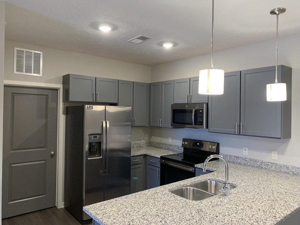 Kitchen with slate gray cabinets and matching stainless steel appliances at The Villas at Mahoney Park