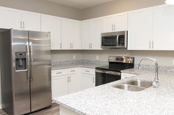 A kitchen with a stainless steel refrigerator and a granite countertop.