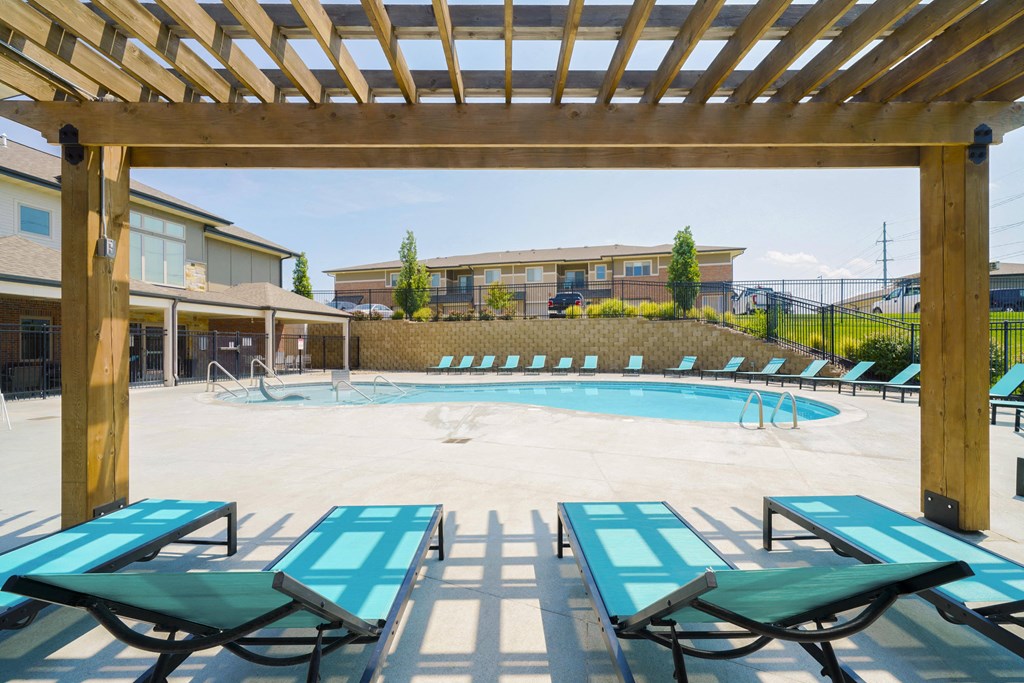lounge chairs under a pergola overlooking a resort-style pool
