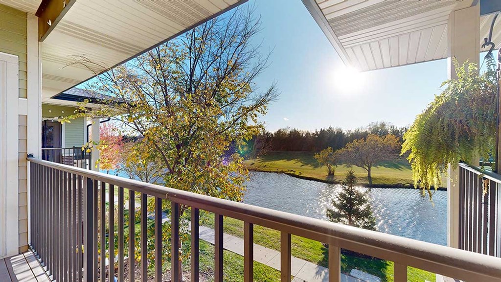 a balcony with a view of a pond at the neighboring golf course