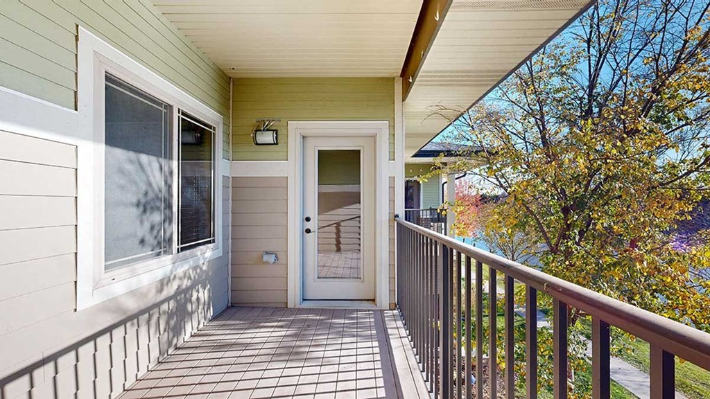 a balcony overlooking a pond with a window to the bedroom and a door to the living room