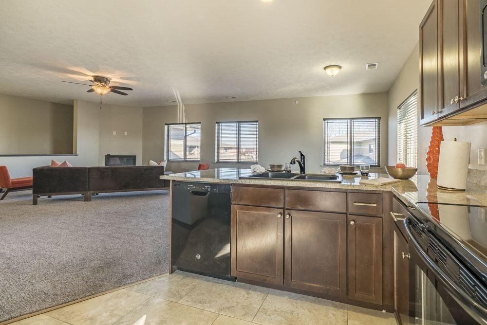 A kitchen with a black fridge and brown cabinets.