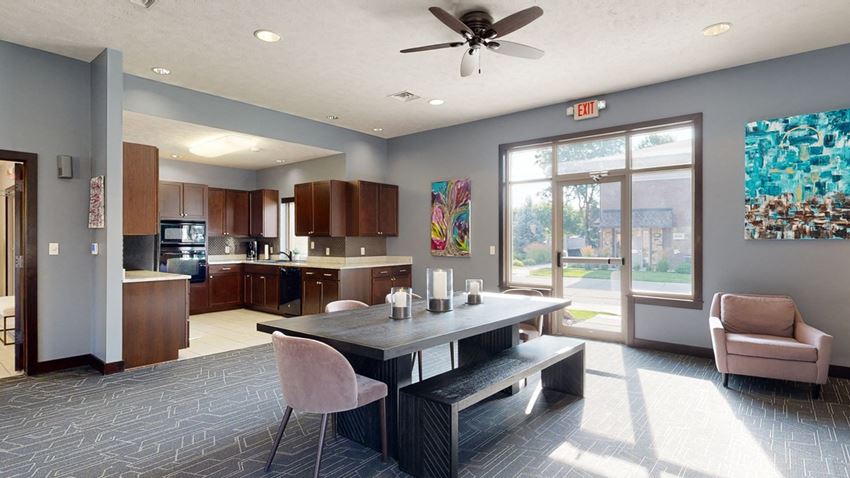 a dining area in the clubhouse with a table and chairs and a kitchen in the background