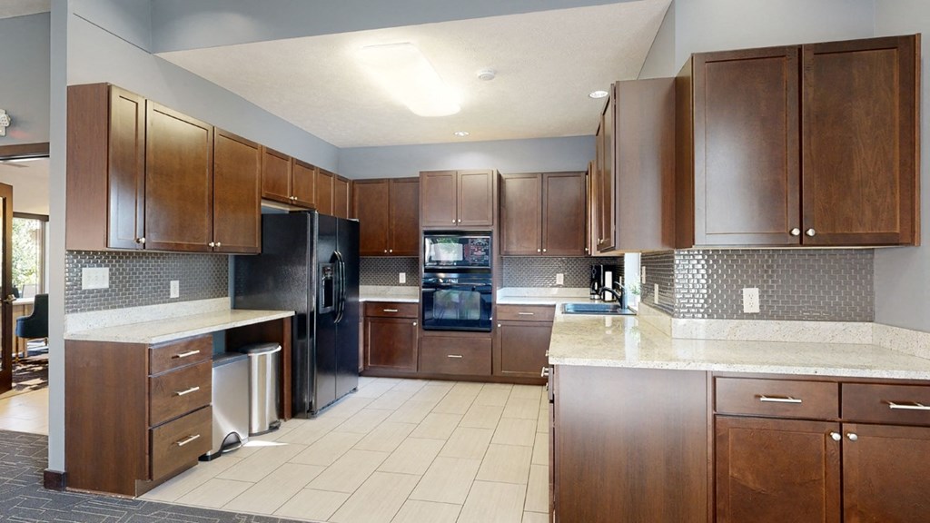 a clubhouse kitchen with brown cabinets and a white tile floor