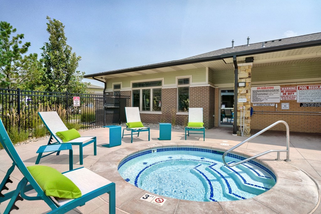 Round hot tub with step walk-in and turquoise lounge chairs around it