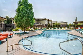 Organically shaped resort style pool surrounded a pool deck with bright blue lounge chairs - Photo Gallery 6