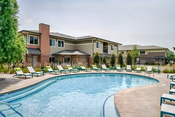 Organically shaped resort style pool surrounded a pool deck with bright blue lounge chairs - Photo Gallery 14