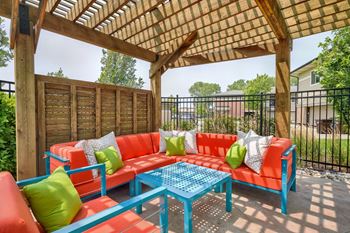 Wood pergola area with bright orange and turquoise lounge furniture positioned under it