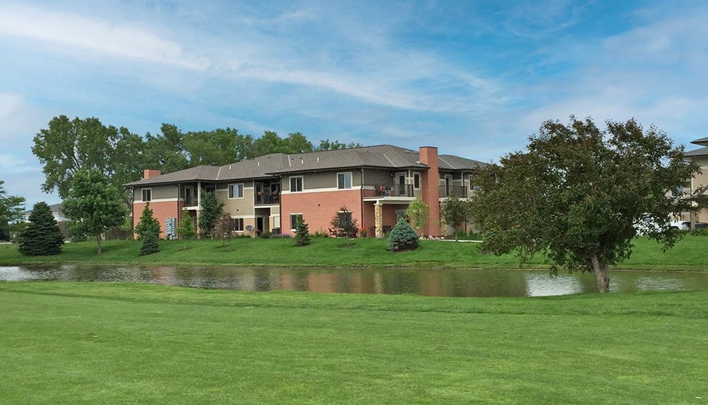 An apartment building with a pond in front of it