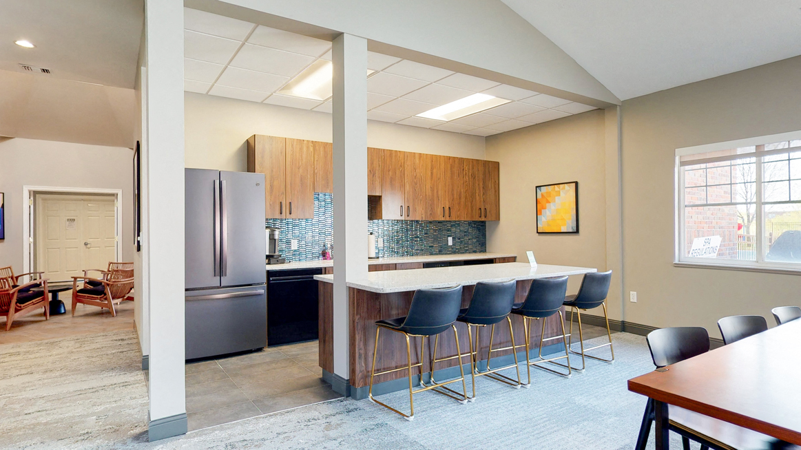Community clubhouse kitchen with refrigerator and island seating for resident use in the clubhouse at The Northbrook Apartments