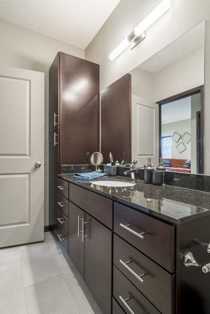 A bathroom with a sink, mirror, and cabinets.