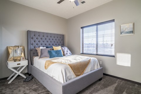 A bedroom with a large bed and a window with blinds.