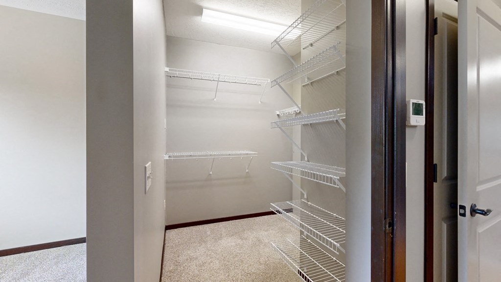 a walk-in closet in the bedroom with lots of shelves