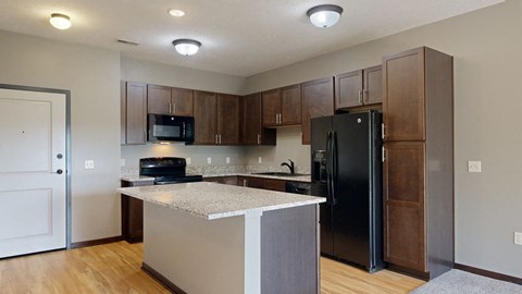 a kitchen with dark cabinets, black appliances, and light granite countertops