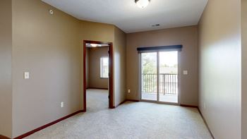 an living room with a  sliding glass door to the balcony and an open door to a bedroom