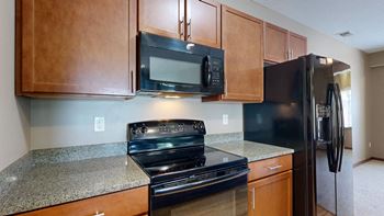 a kitchen with black GE appliances and granite counter tops