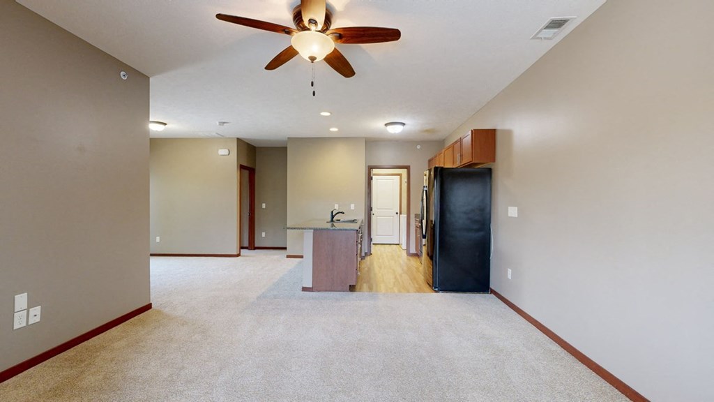a living room with a ceiling fan in front of a galley kitchen