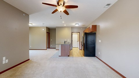 a living room with a ceiling fan in front of a galley kitchen